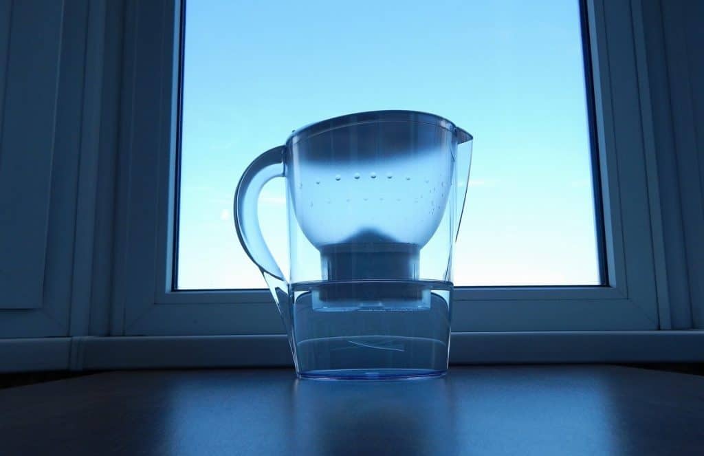 Jarra filtradora de agua Brita o jarra Jatta a contraluz en una ventana