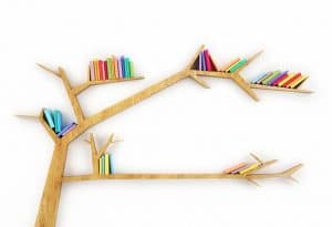 Estantería de madera en forma de árbol con libros de colores en sus ramas, sobre un fondo blanco